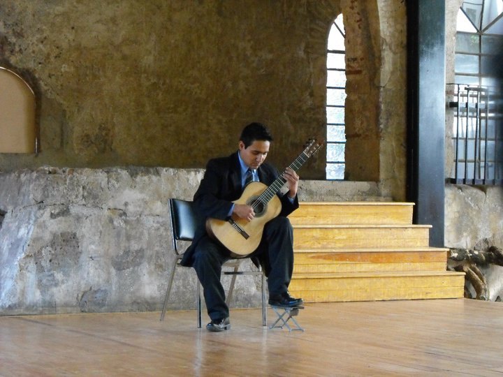 Guitarrista interpretando en un interior de arquitectura histórica